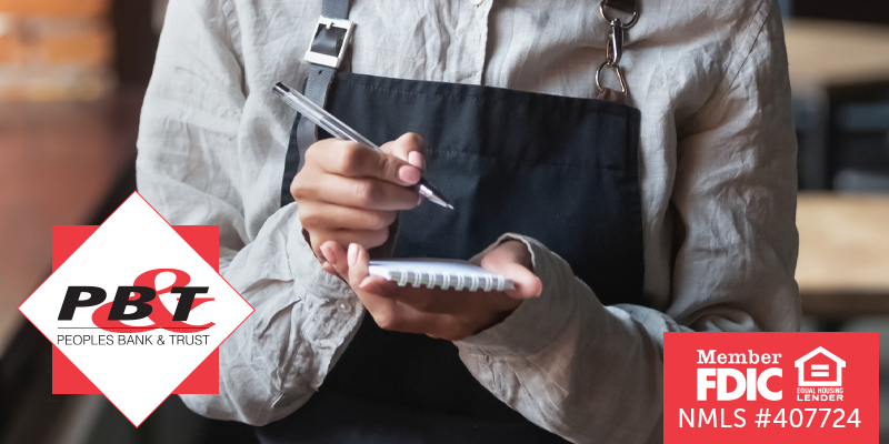 Waitress in black apron writing on paper pad with pen