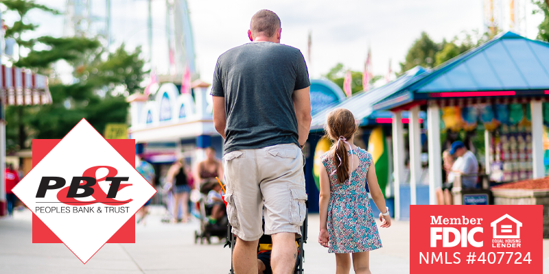 Dad pushing stroller with his daughter walking next to him at outdoor event